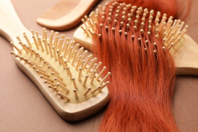 Photo of Wooden brushes and lock of hair on beige background, closeup