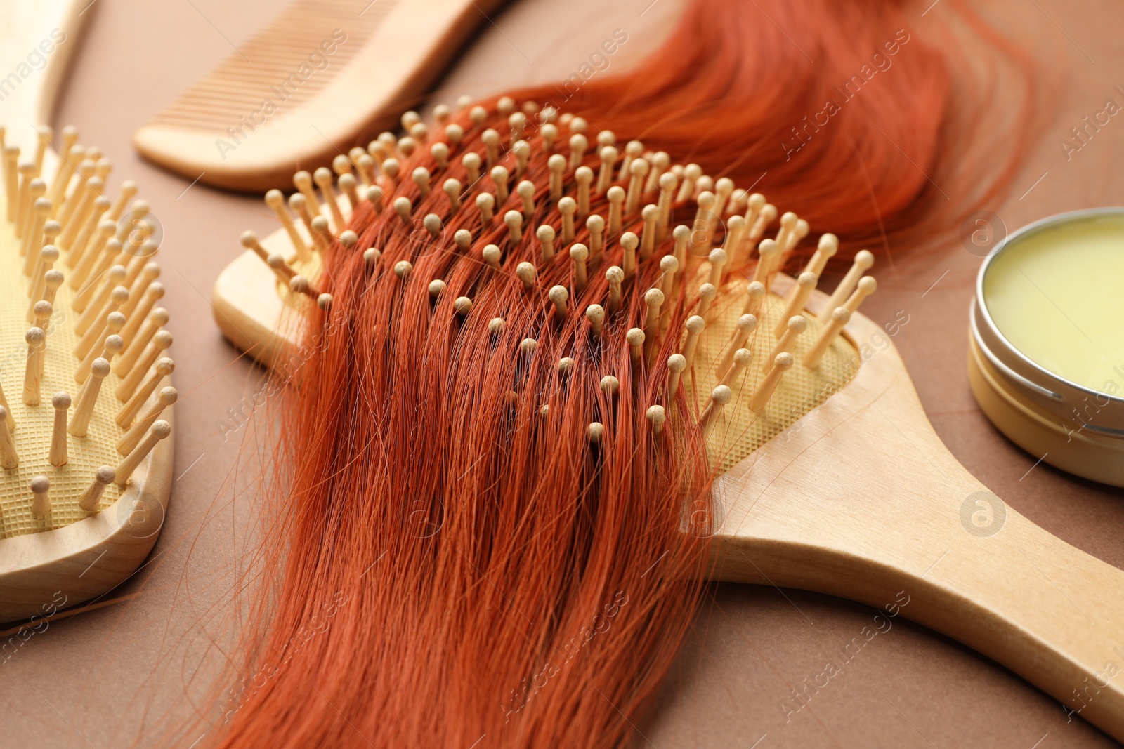 Photo of Wooden brushes and lock of hair on beige background, closeup