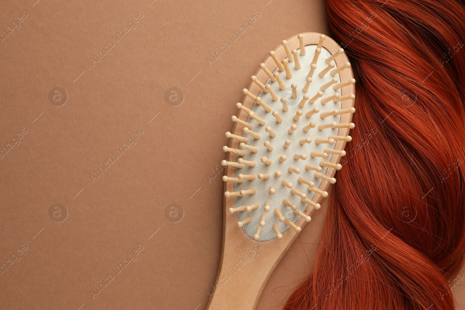 Photo of Wooden brush and lock of hair on beige background, top view. Space for text