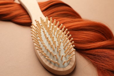 Photo of Wooden brush and lock of hair on beige background, closeup