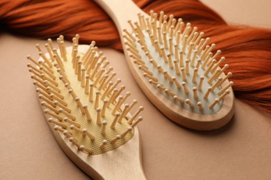 Photo of Wooden brushes and lock of hair on beige background, closeup