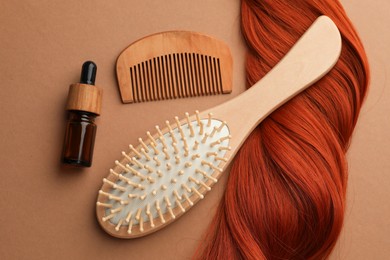 Photo of Wooden brush, comb, serum and lock of hair on beige background, flat lay