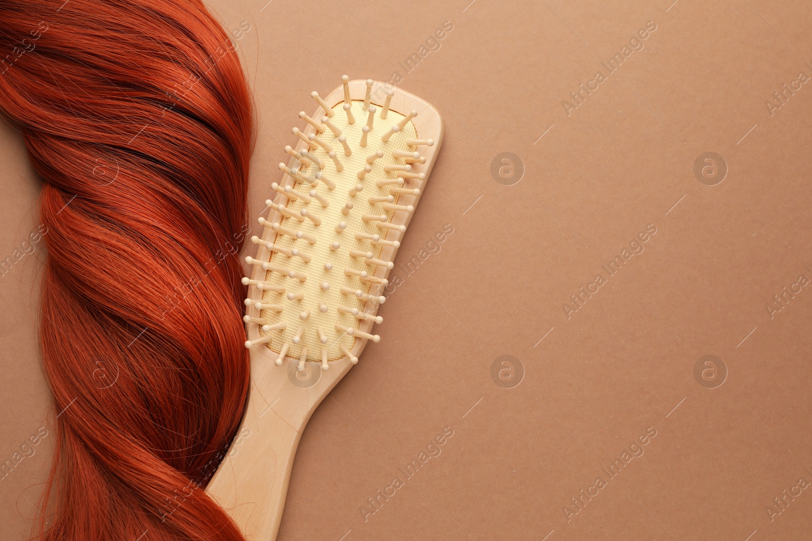 Photo of Wooden brush and lock of hair on beige background, top view. Space for text