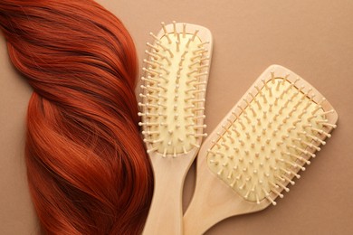 Photo of Wooden brushes and lock of hair on beige background, flat lay