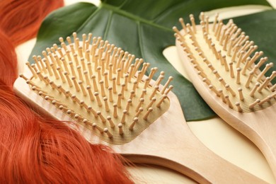 Photo of Wooden brushes, lock of hair and monstera leaf on beige background, closeup