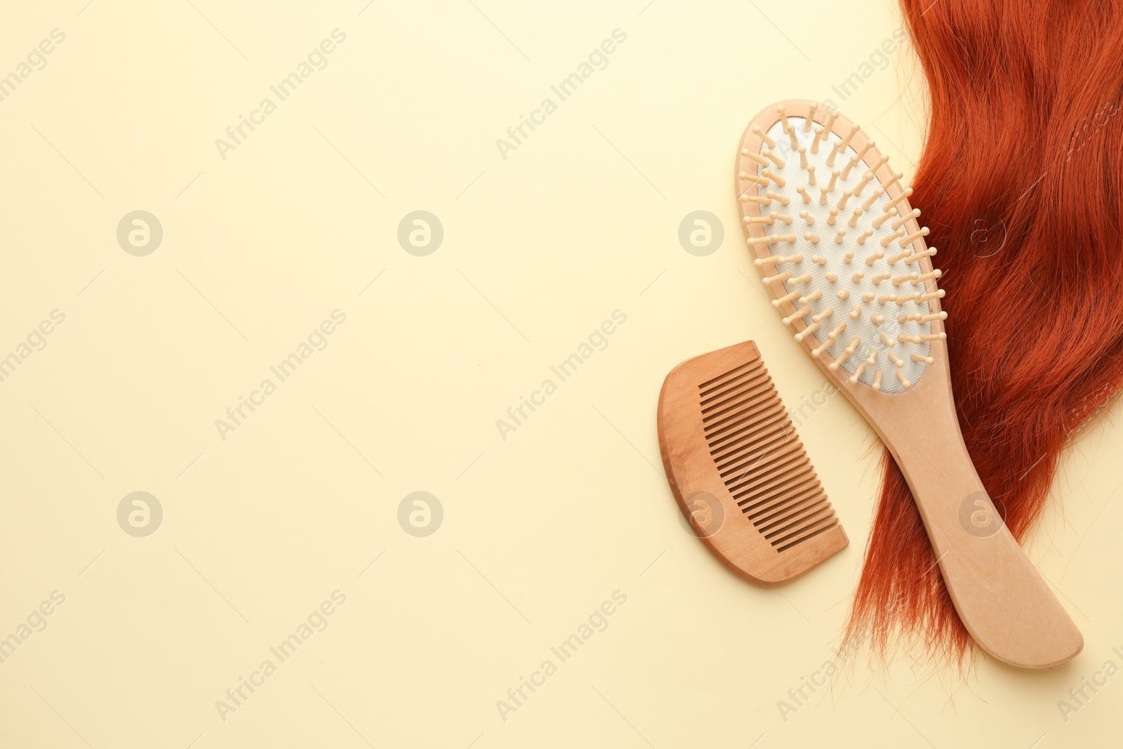 Photo of Wooden brush, comb and lock of hair on beige background, flat lay. Space for text