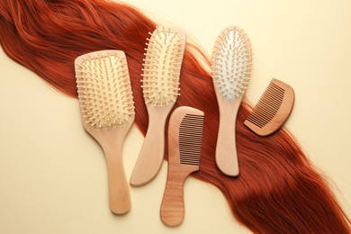 Photo of Set of different wooden brushes, combs and lock of hair on beige background, flat lay