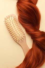 Photo of Wooden brush and lock of hair on beige background, top view