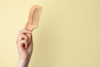 Photo of Woman with wooden comb on beige background, closeup. Space for text