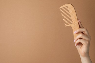 Photo of Woman with wooden comb on beige background, closeup. Space for text