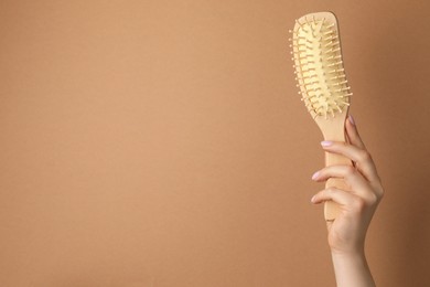 Photo of Woman with wooden brush on beige background, closeup. Space for text