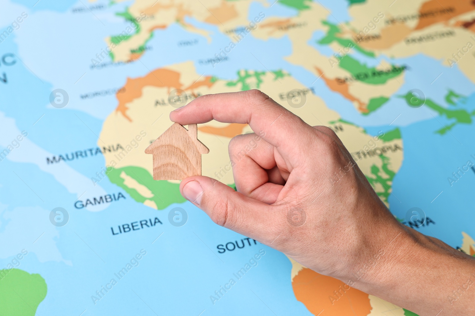 Photo of Woman holding wooden house model on world map, closeup. Accommodation search