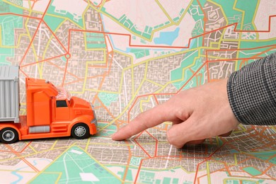 Photo of Woman pointing at city map with toy truck, closeup. Logistics concept