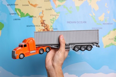 Photo of Woman holding toy truck against world map, closeup. Logistics concept