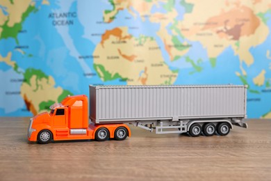 Photo of Toy truck on wooden table against world map. Logistics concept