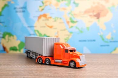 Photo of Toy truck on wooden table against world map. Logistics concept