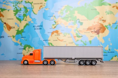 Photo of Toy truck on wooden table against world map. Logistics concept