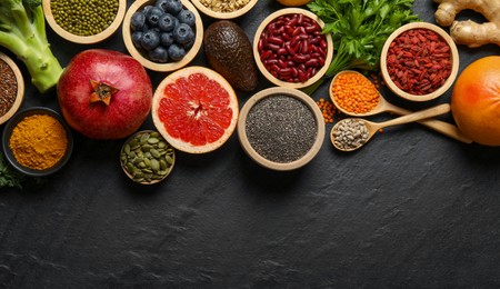 Photo of Superfood. Different healthy food products on grey table, flat lay. Space for text