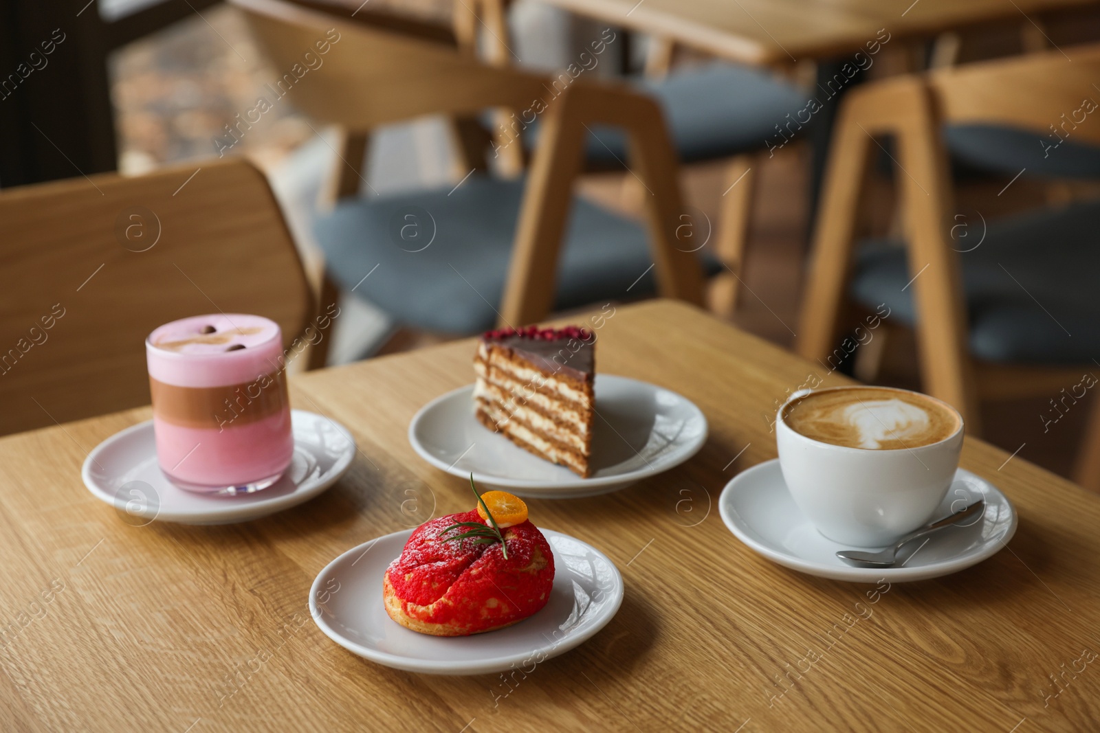 Photo of Aromatic coffee and delicious desserts served on wooden table in cafe