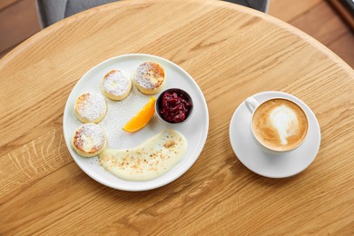 Photo of Delicious cottage cheese pancakes and coffee served on wooden table, top view