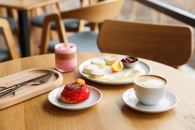 Photo of Delicious cottage cheese pancakes, dessert and coffee served on wooden table in cafe