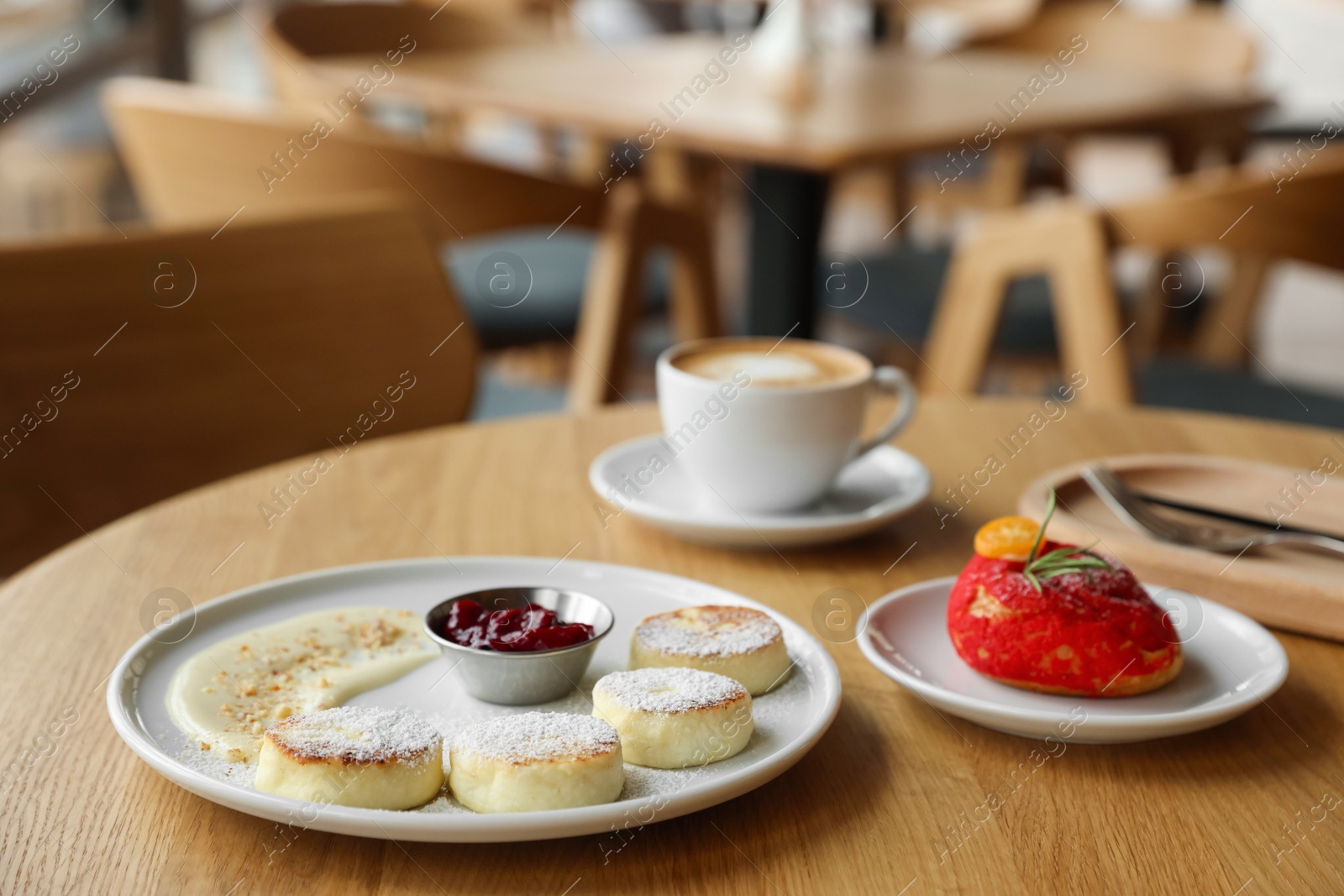 Photo of Delicious cottage cheese pancakes, dessert and coffee served on wooden table in cafe