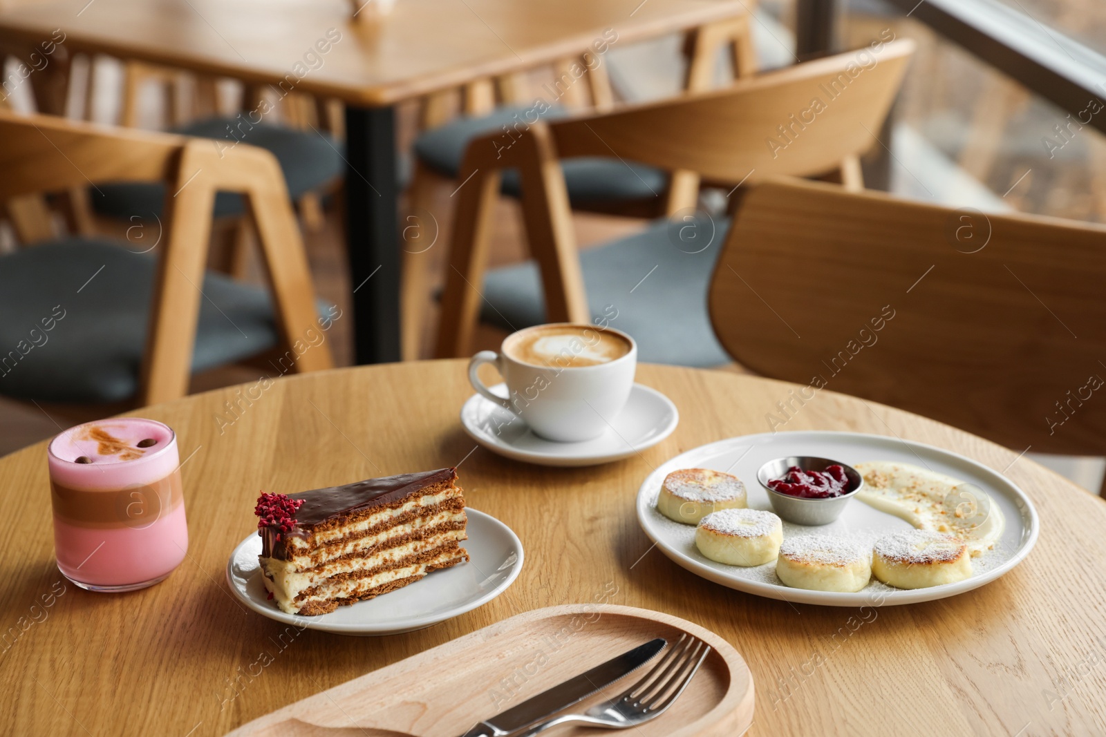 Photo of Delicious cottage cheese pancakes, desserts and aromatic coffee served on wooden table in cafe