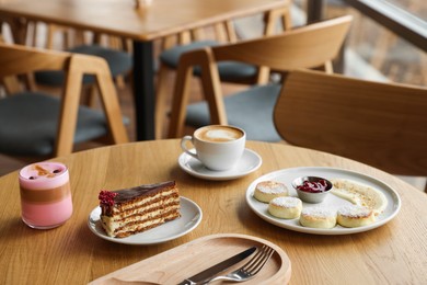 Photo of Delicious cottage cheese pancakes, desserts and aromatic coffee served on wooden table in cafe