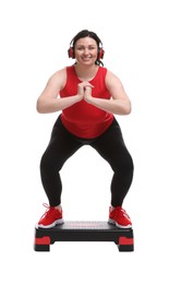 Photo of Plus size woman in gym clothes doing exercise with step platform on white background