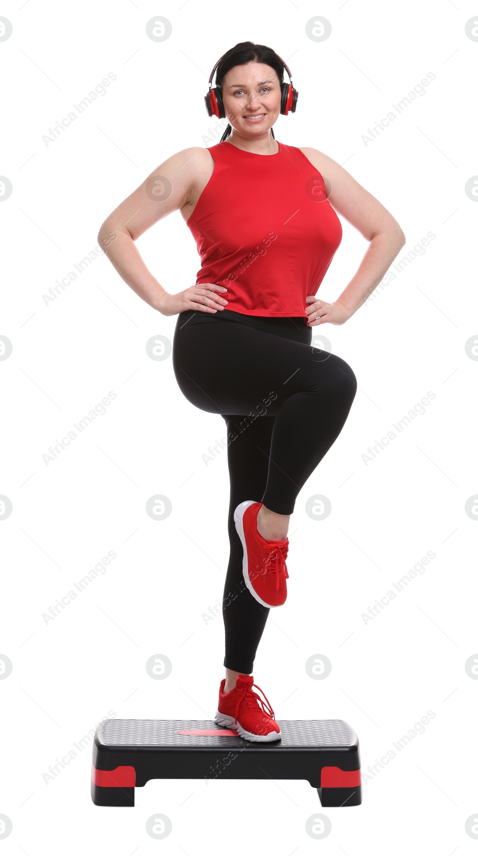 Photo of Plus size woman in gym clothes doing exercise with step platform on white background