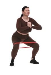 Photo of Plus size woman in gym clothes doing exercise with elastic band on white background