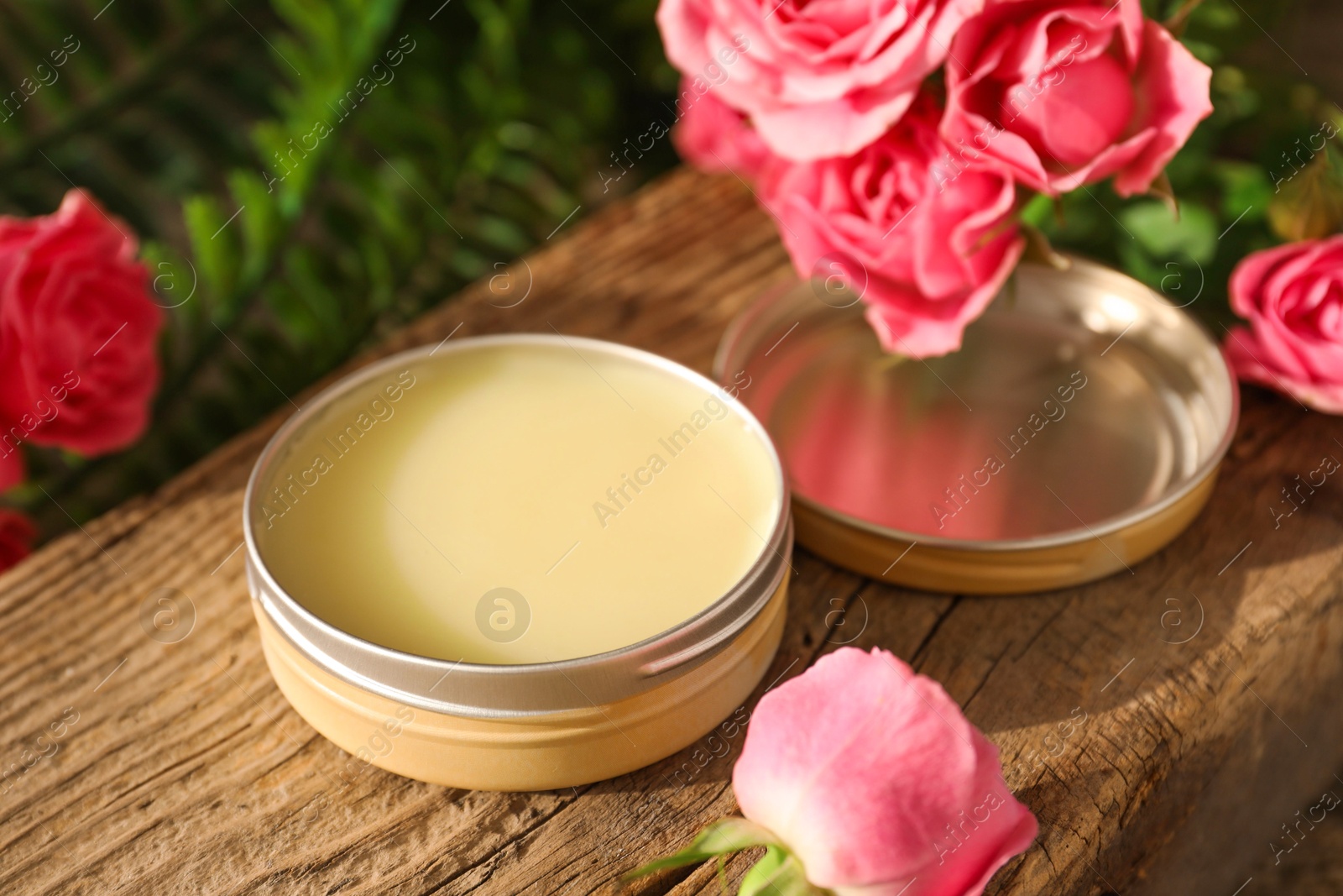 Photo of Natural solid perfume and pink roses on wood, closeup