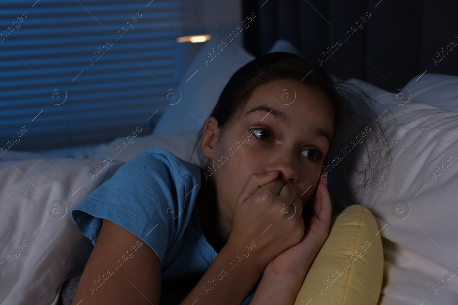 Photo of Fearful girl lying on bed at night