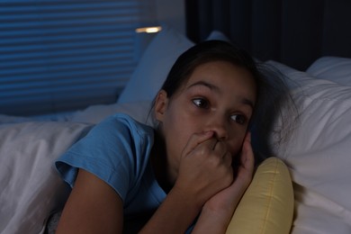 Photo of Fearful girl lying on bed at night