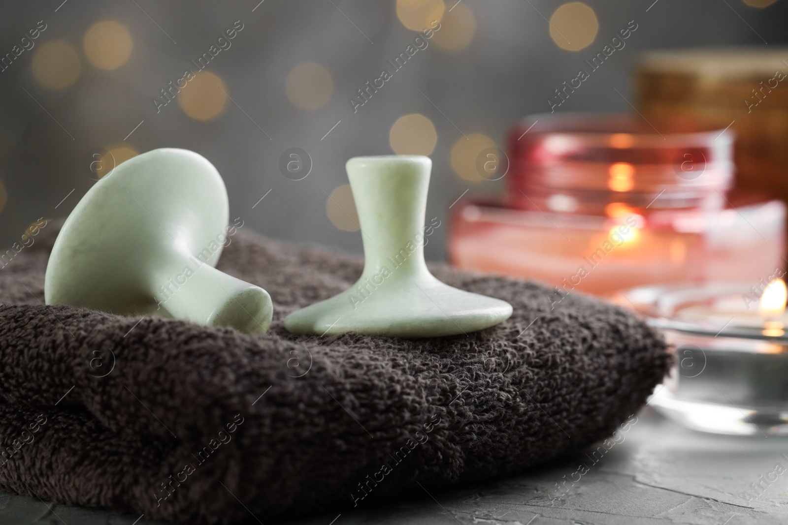 Photo of Spa stones, towel and burning candles on grey table, closeup