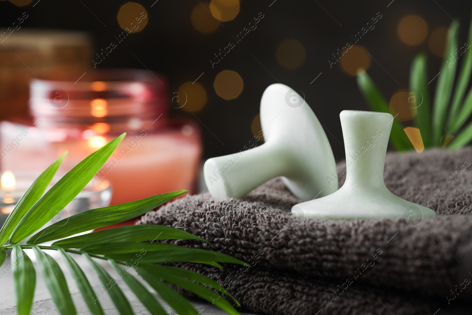 Photo of Spa stones, towel and green leaves on table, closeup