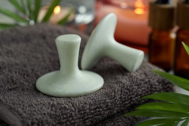 Photo of Spa stones, towel and green leaf on table, closeup