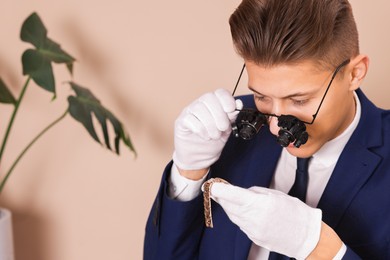 Photo of Appraiser evaluating luxury wristwatch on beige background