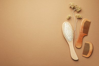 Photo of Wooden hair brush, combs and dried flowers on beige background, flat lay. Space for text