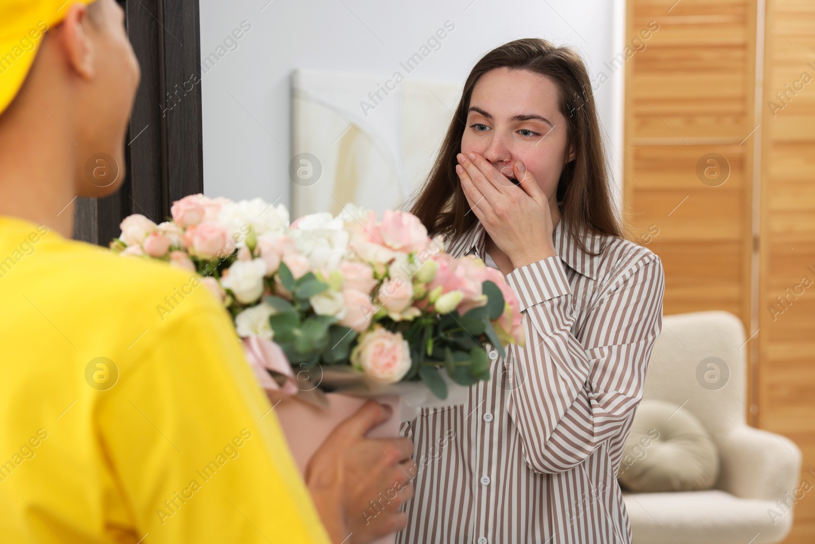 Photo of Delivery man giving gift box with beautiful floral composition to surprised woman at door, closeup