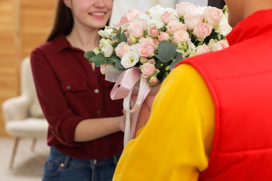 Photo of Delivery man giving gift box with beautiful floral composition to happy woman, selective focus