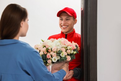 Smiling delivery man giving gift box with beautiful floral composition to woman at door