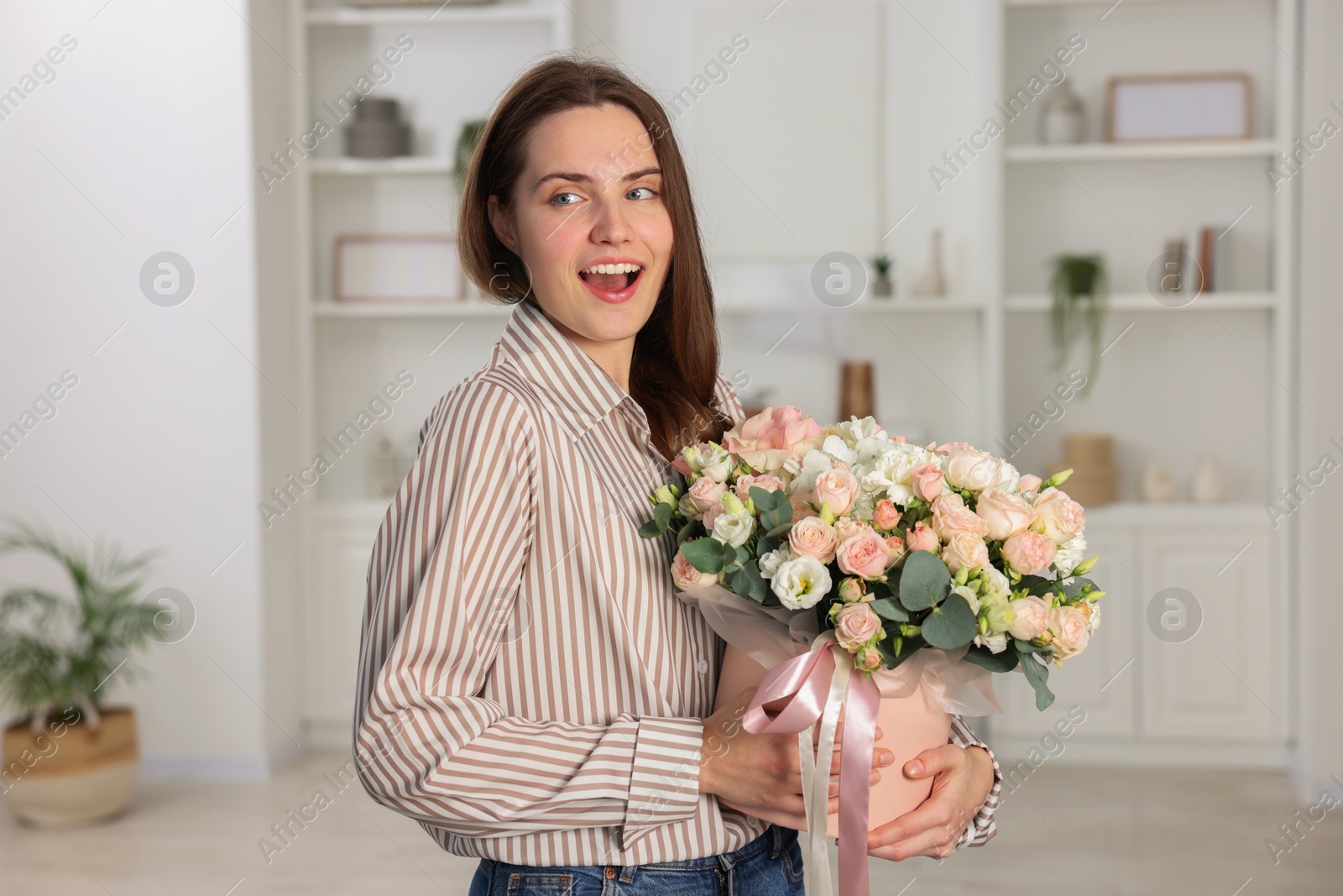 Photo of Portrait of beautiful woman holding delivered gift box with floral composition indoors