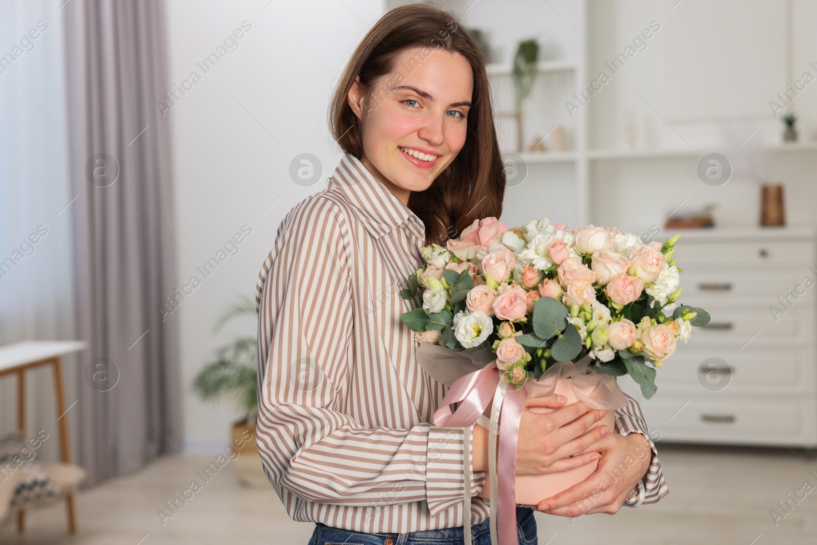 Photo of Portrait of smiling woman holding delivered gift box with floral composition indoors