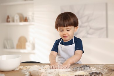 Photo of Cute little boy making dough at table indoors