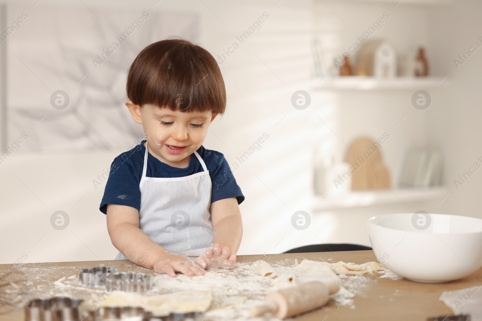 Photo of Cute little boy making dough at table indoors