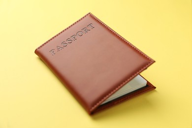 Photo of Passport in bright cover on yellow background, closeup