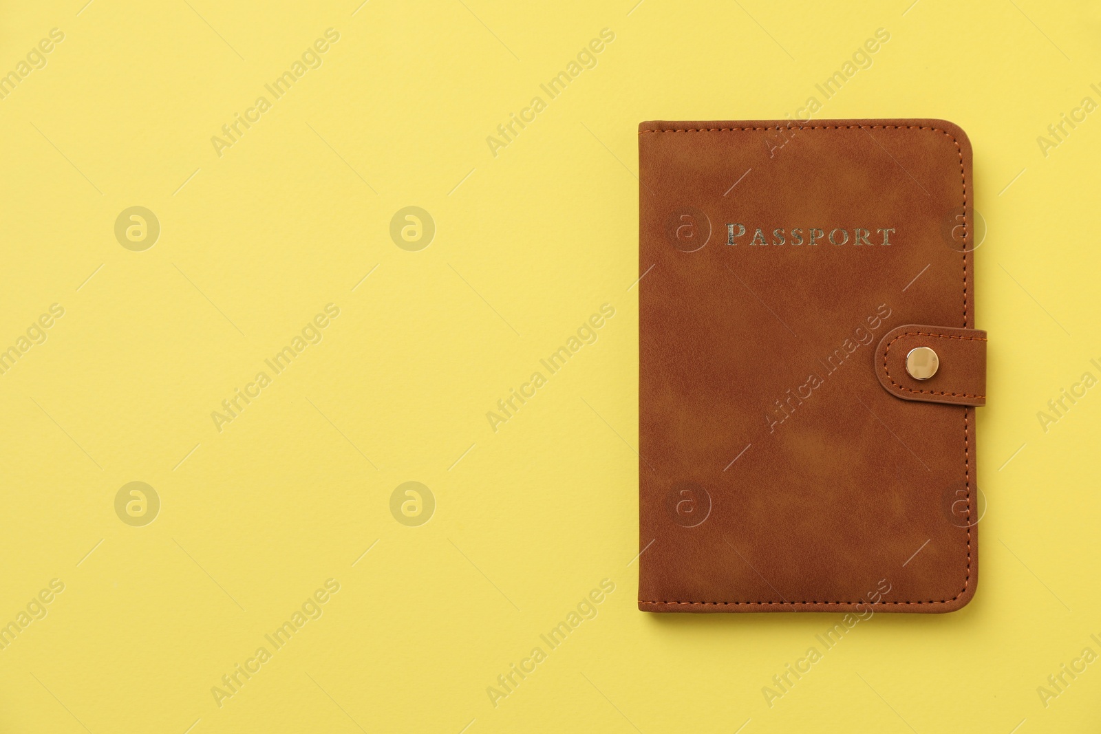 Photo of Passport in leather cover on yellow background, top view. Space for text