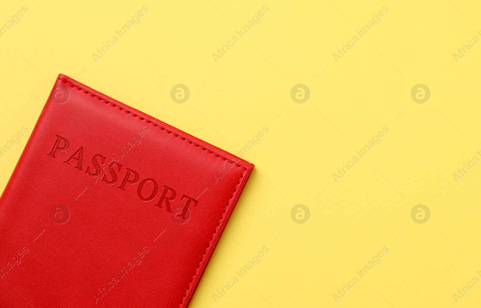 Photo of Passport in bright cover on yellow background, top view. Space for text