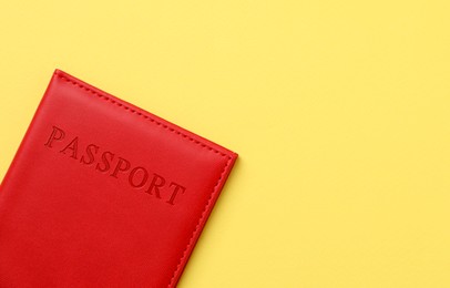 Photo of Passport in bright cover on yellow background, top view. Space for text